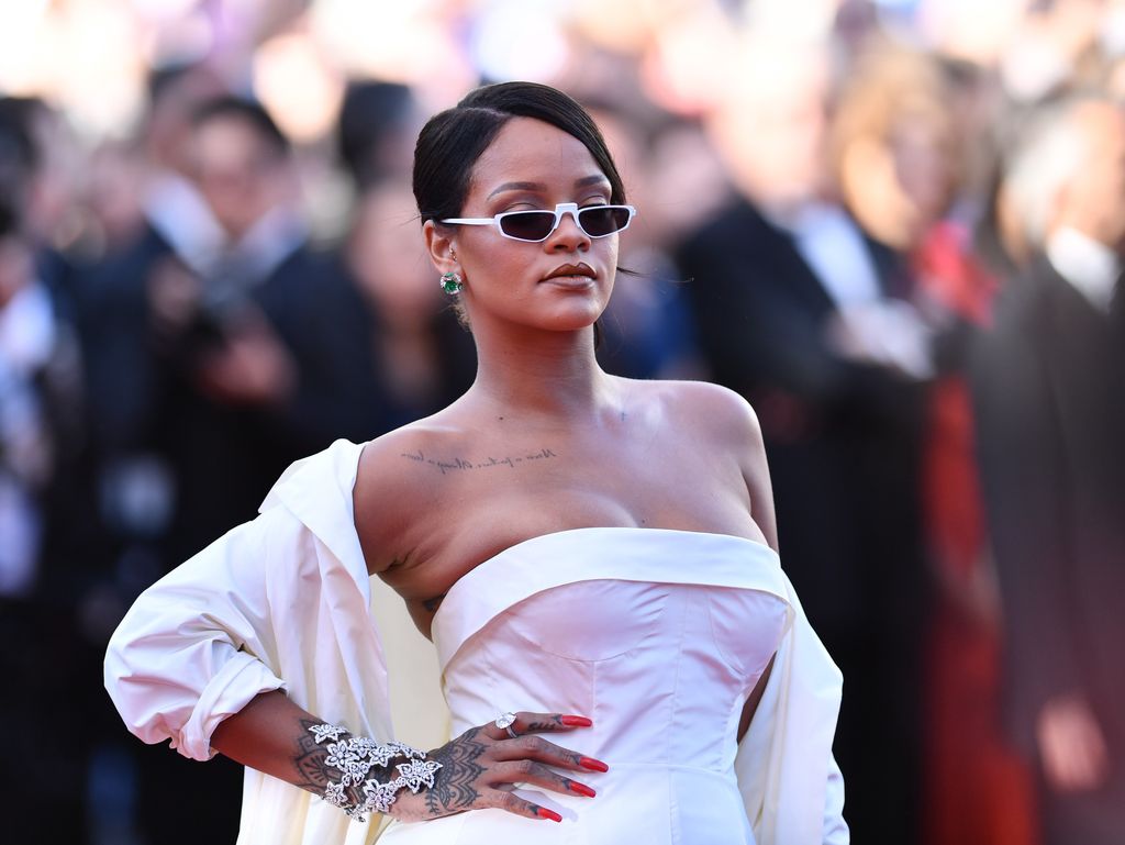 Rihanna wearing a white strapless dress showing off her collarbone tattoo