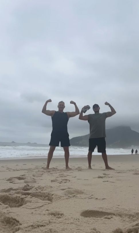Sam Champion and Rubem Robierb flexing their arms on beach