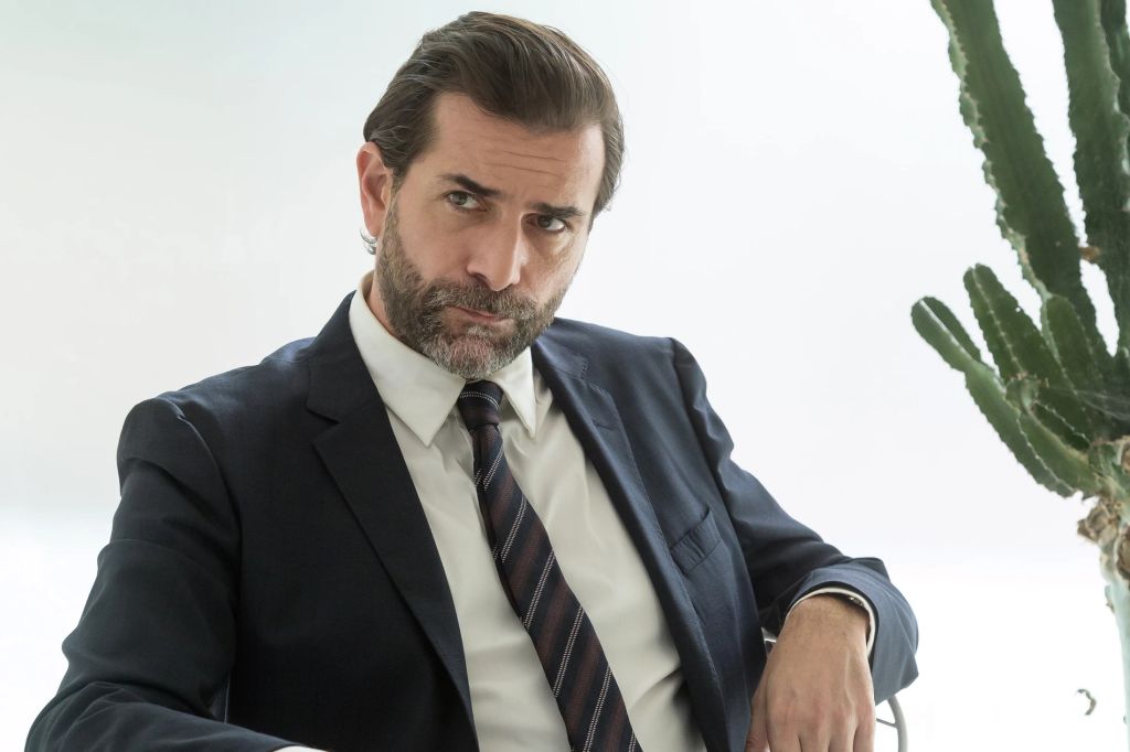 man in suit sitting in white room