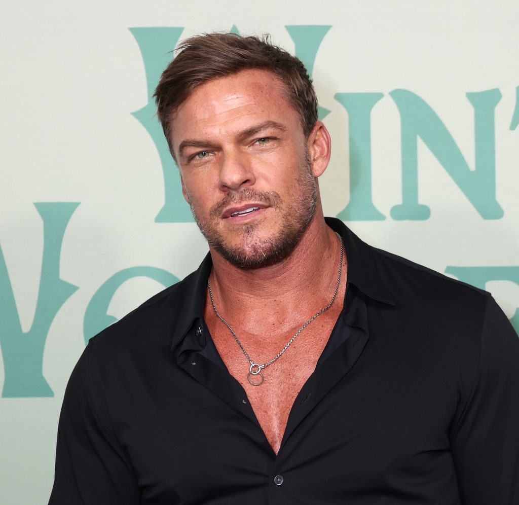 Alan Ritchson black shirt unbuttoned, muscular physique