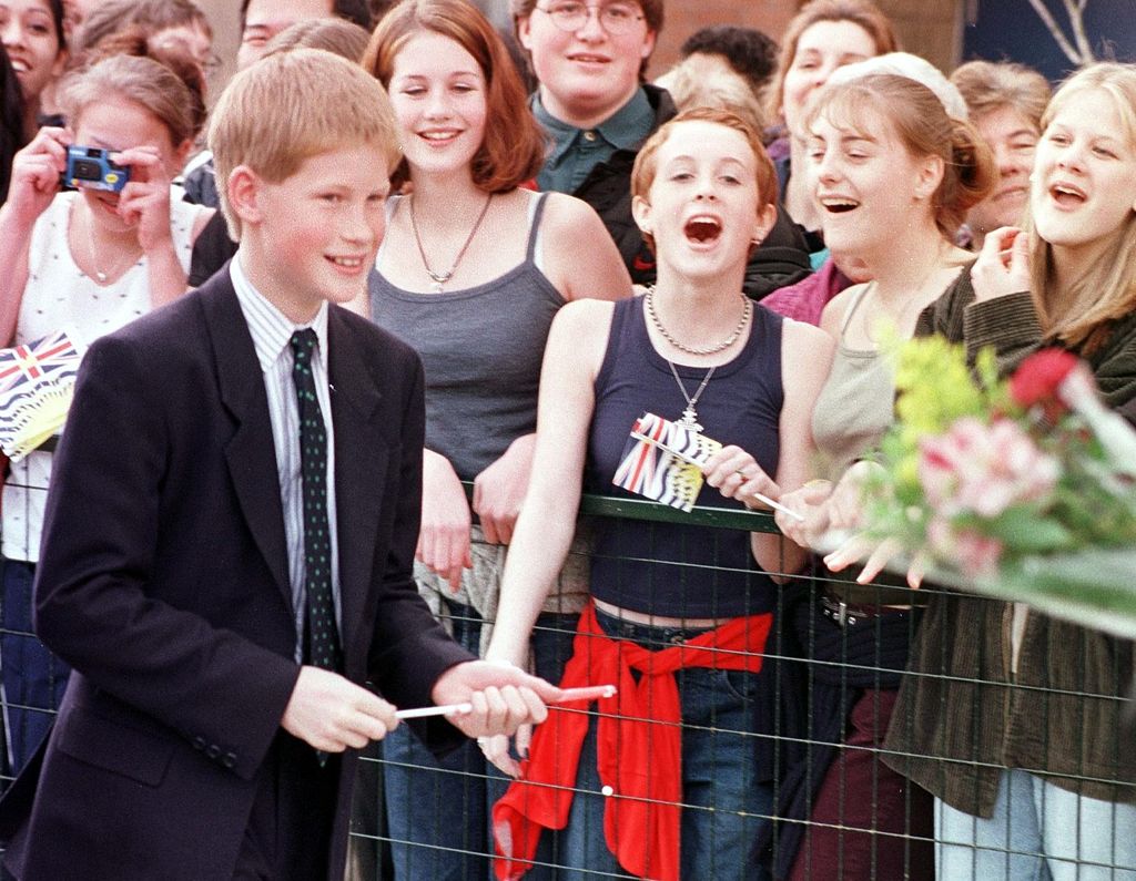 Prince Harry walks past cheering teenage girls