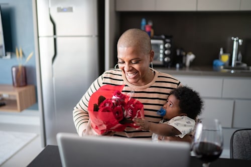 Mother with baby son receiving roses from boyfriend during video call
