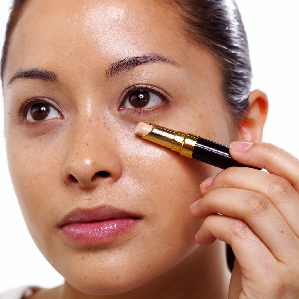 Woman putting on under eye concealer