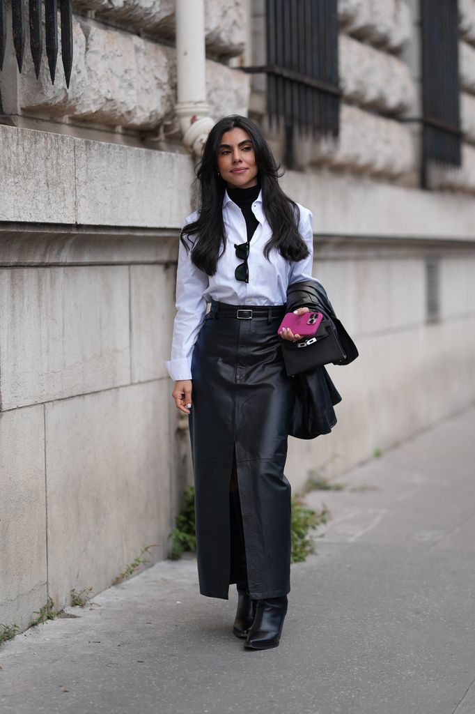 A guest wears a black turtleneck pullover, a white shirt, a black leather belt, black leather long skirt with a slit, black leather boots, outside Hermes, during Womenswear Spring/Summer 2025 as part of  Paris Fashion Week on September 28, 2024 in Paris, France. (Photo by Edward Berthelot/Getty Images)