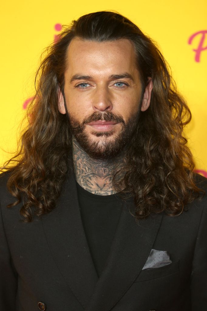 man posing on red carpet with long hair 