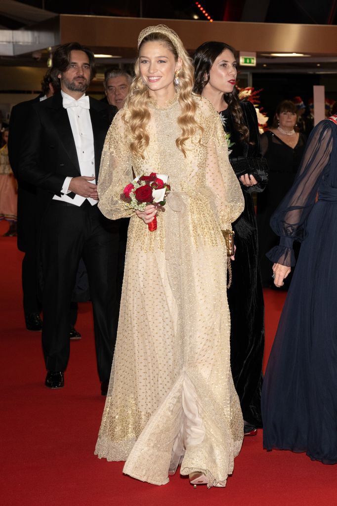 Beatrice Borromeo glows in a sheer, gold-embellished gown with puffed sleeves and matching headband at a red carpet gala.