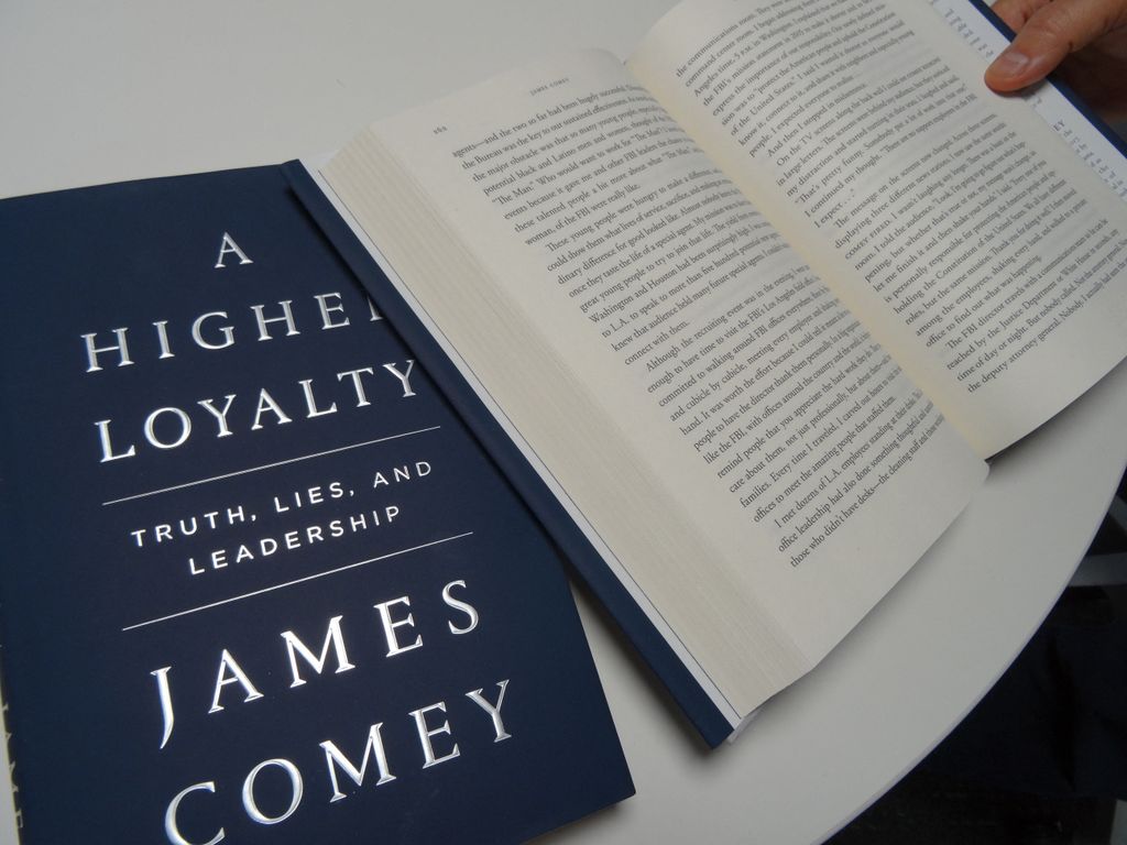 A journalist reads "A Higher Loyalty: Truth, Lies and Leadership" by James Comey on April 16, 2018
