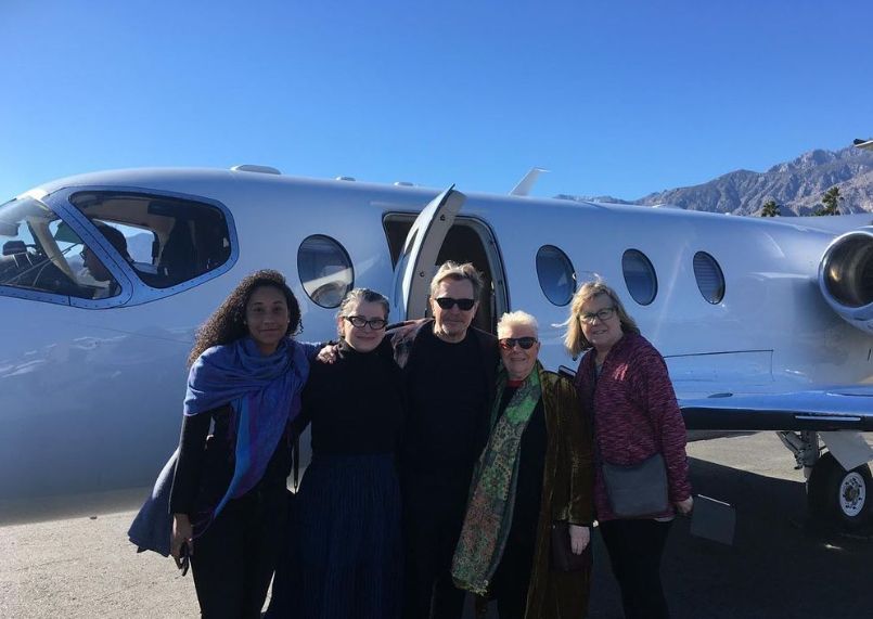 Gary Oldman and Laila Morse with three women in front of a small plane