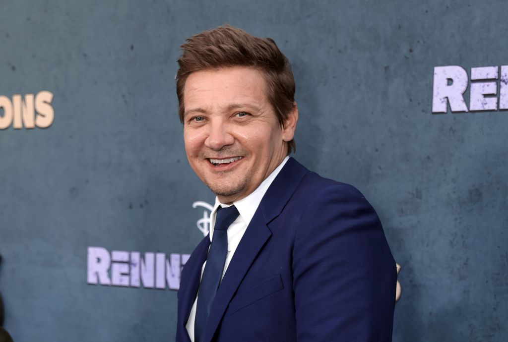 Jeremy Renner smiling for a photo on a red carpet