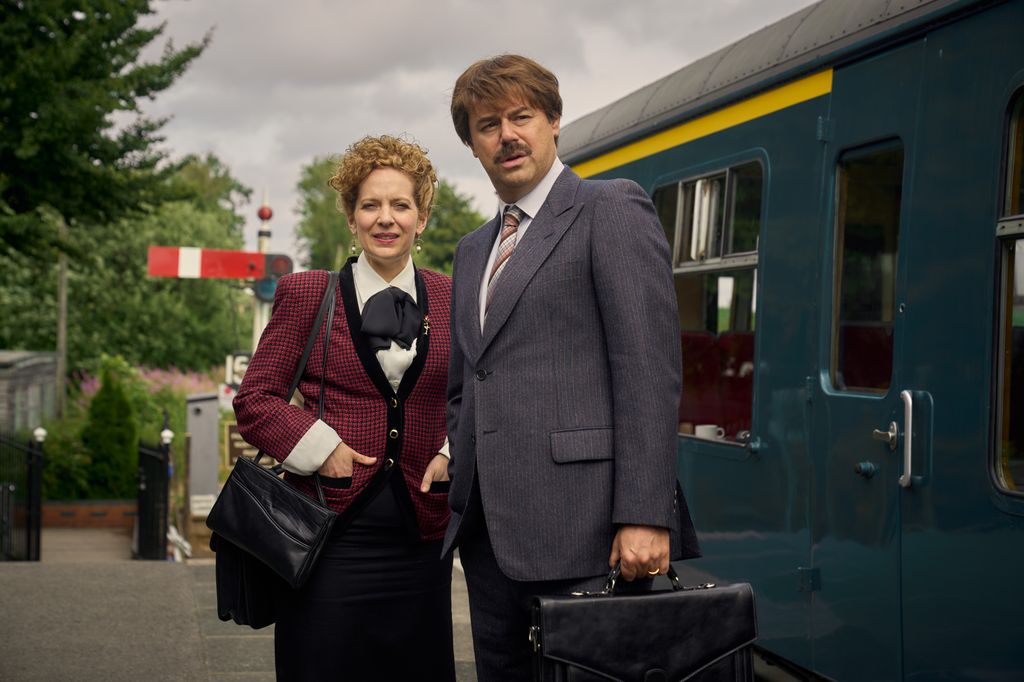Two people stand outside a train station