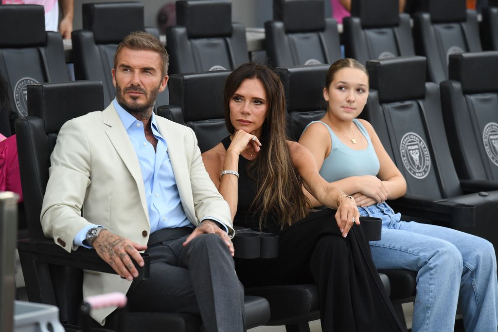 Harper, David and Victoria Beckham looking serious at a football game