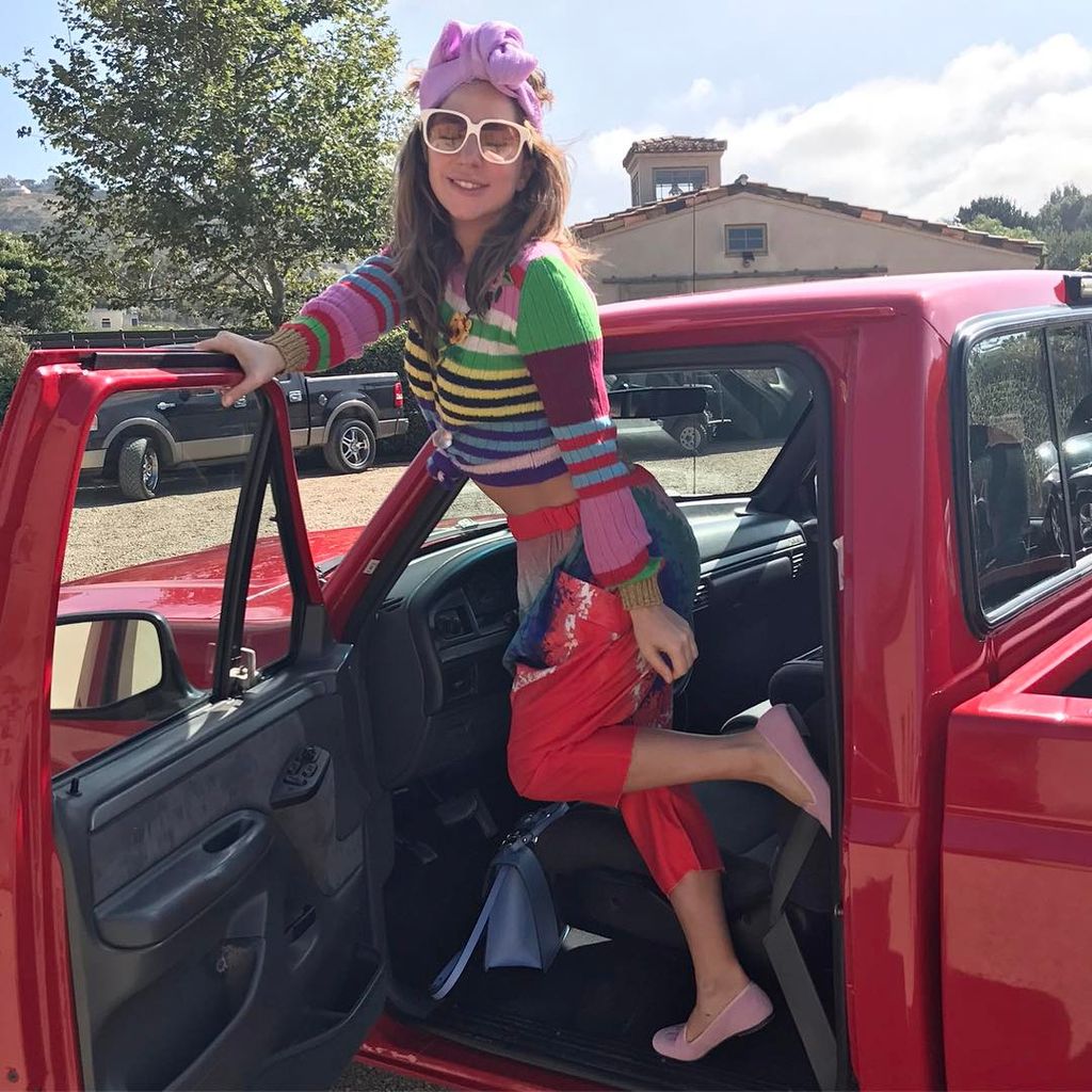 Lady Gaga in colourful outfit posing with red car