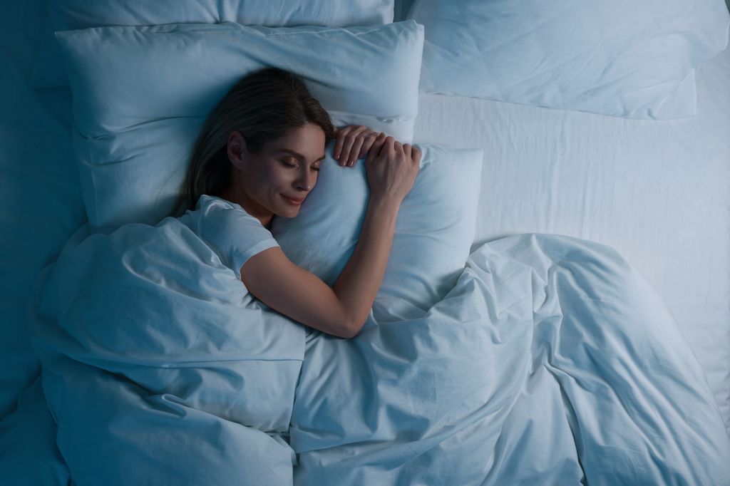 woman sleeping  in bed at night hugging pillow