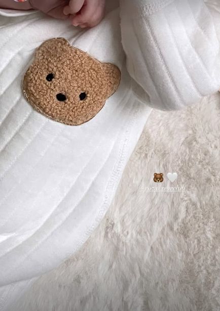 A baby girl sleeping in a onesie with a bear face