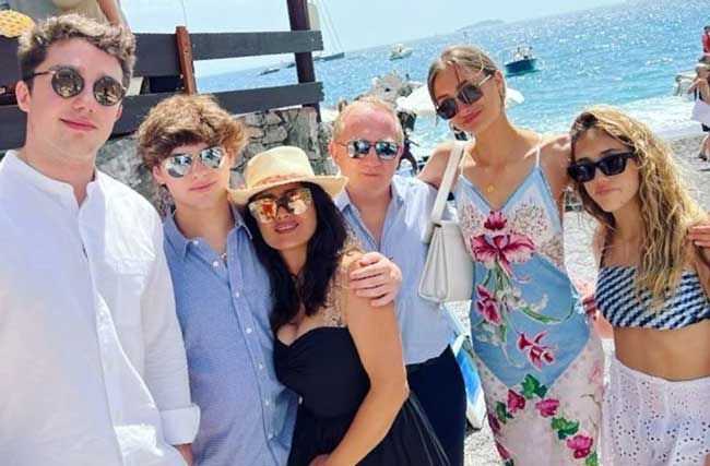 Salma on a sunny beach in sunglasses surrounded by her whole blended family