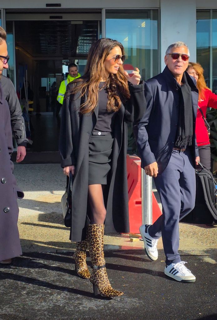 Amal Clooney vient de porter ses bottes les plus audacieuses à ce jour lors d'une sortie avec son mari George 1 George Clooney en veste et pantalon bleu marine et Amal Clooney en robe noire et bottes à imprimé léopard sont arrivés à l'aéroport de Milan le jour de la cérémonie des Jeux Olympiques d'hiver.