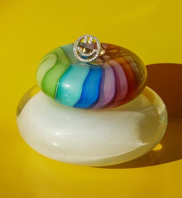 a diamond encrusted ring on a rainbow hued pebble