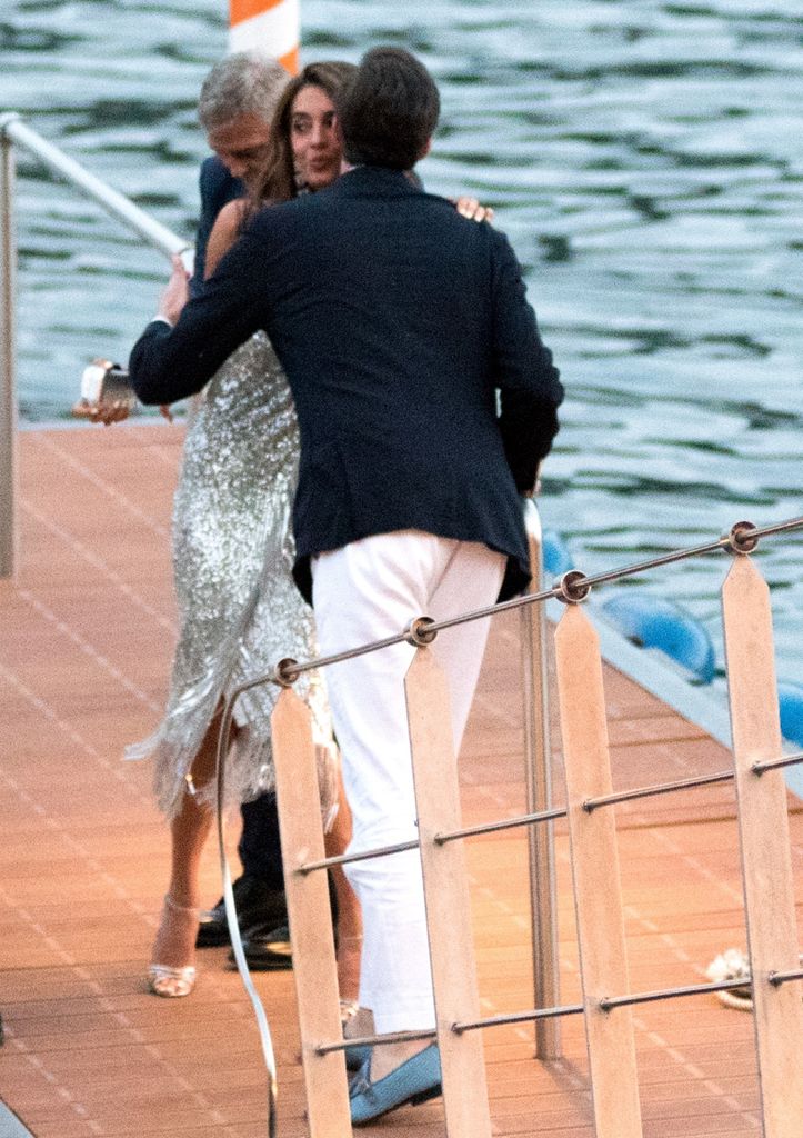 Amal Clooney scintille dans une robe d'été italienne slinky alors que George Clooney révèle qu'il est le gentleman ultime 2 Amal Clooney est accueilli par un ami sur le quai en Italie