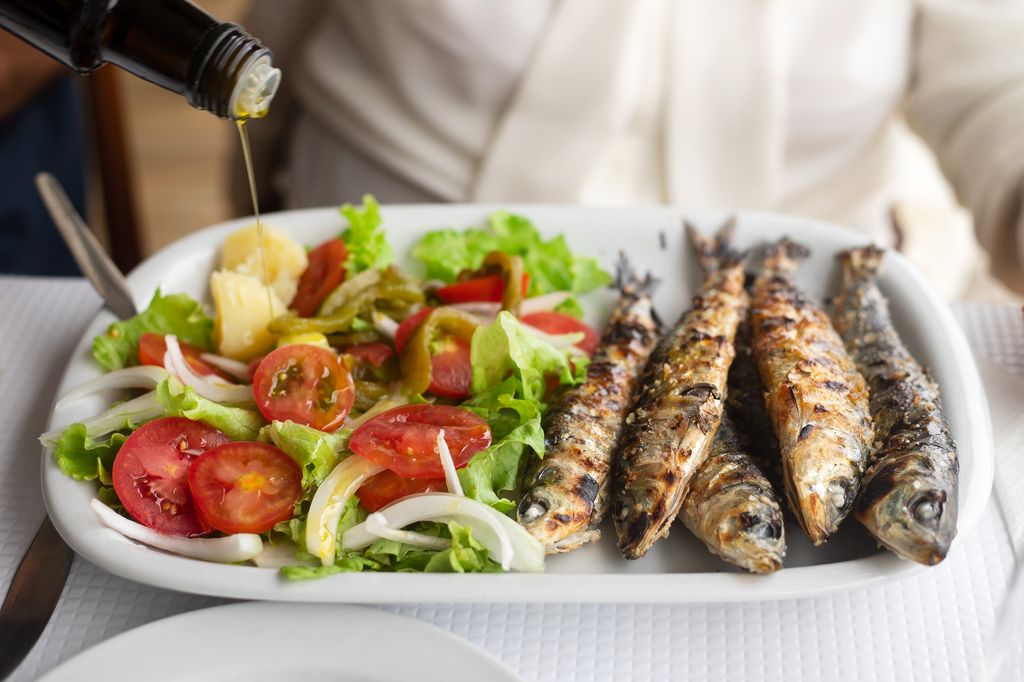 sardines grillées avec salade et huile d'olive sur plat blanc