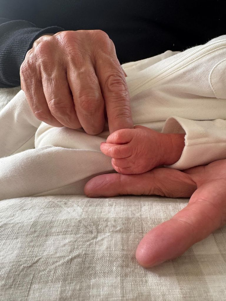 man holding a newborn baby's hand 