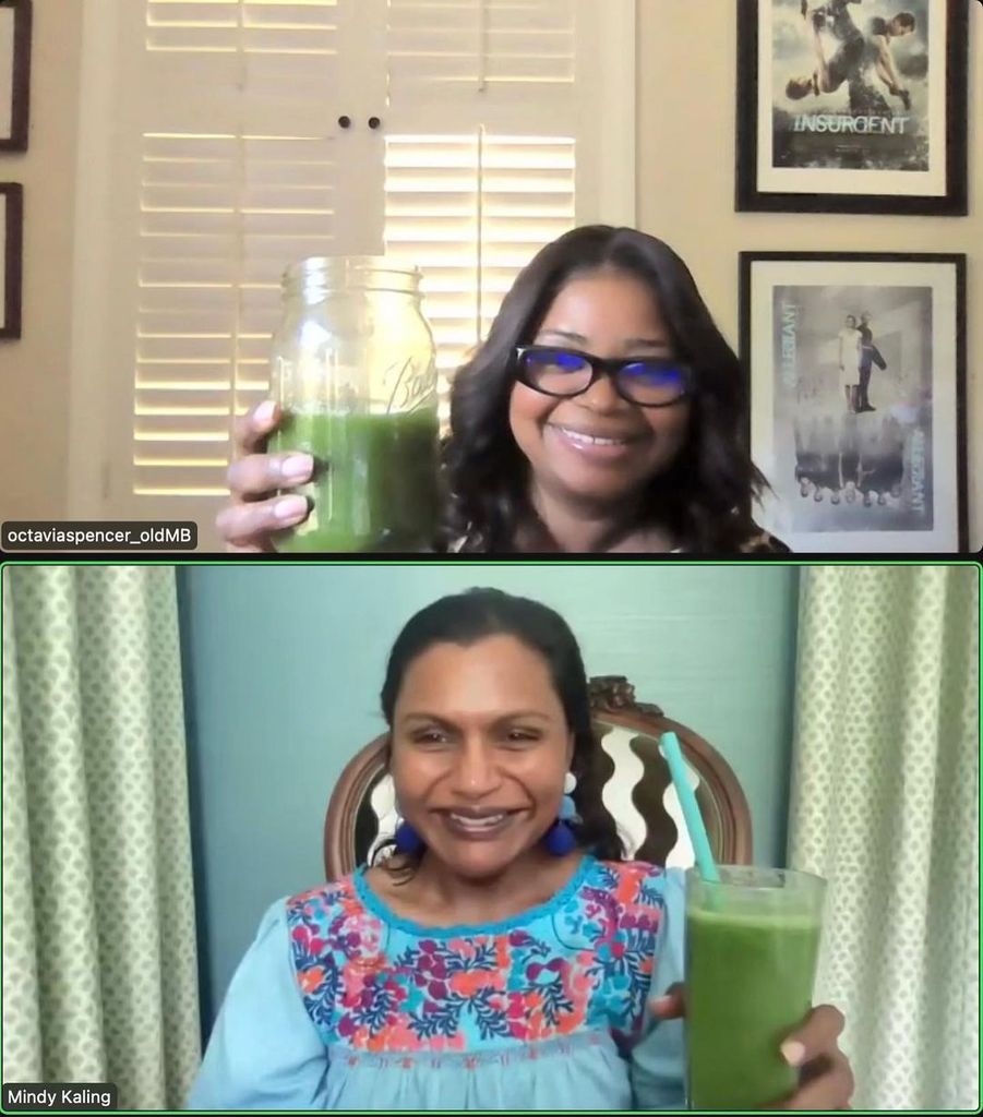 Mindy Kaling holding a green juice in front of green curtains