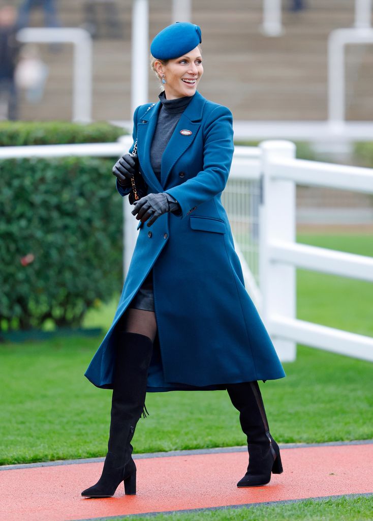 Zara Tindall looking over her shoulder in petrol blue coat and black boots
