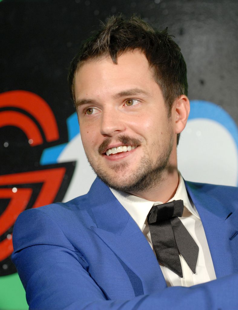 Brandon Flowers in a blue jacket and black bow tie smiling