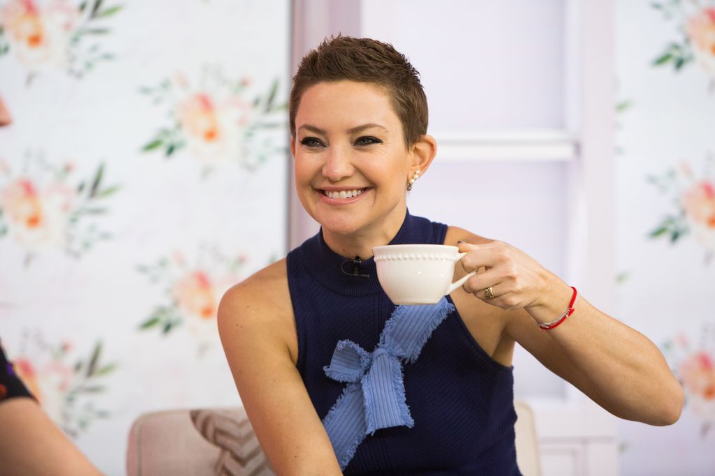 Kate holding cup of tea with short hair and dark eyeliner