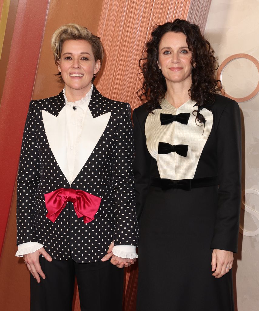 Brandi Carlile and Catherine Shepherd hold hands while walking the red carpet at the 97th Annual Academy Awards