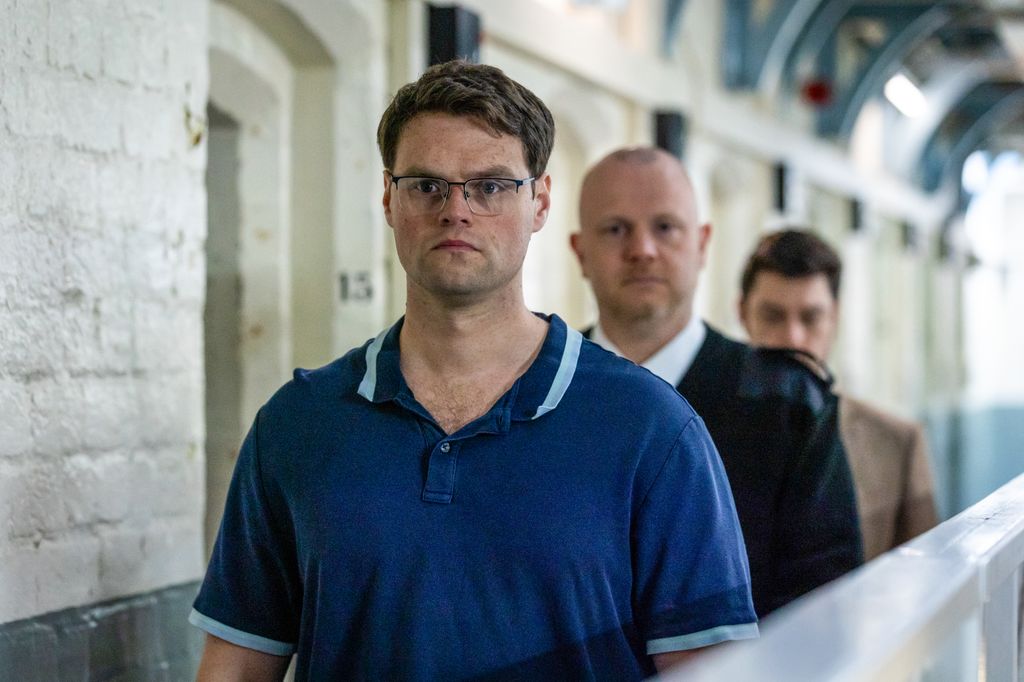 man in blue t-shirt walking through prison