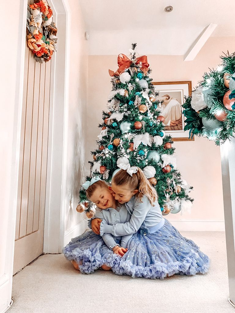 two young girls in front of a Christmas tree