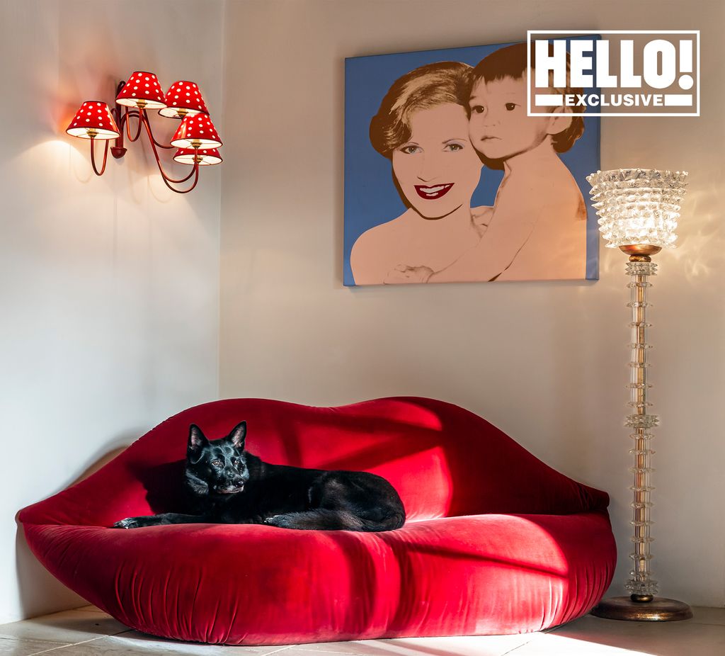 Suzanne Syz home featuring black dog sleeping on red lip shaped couch