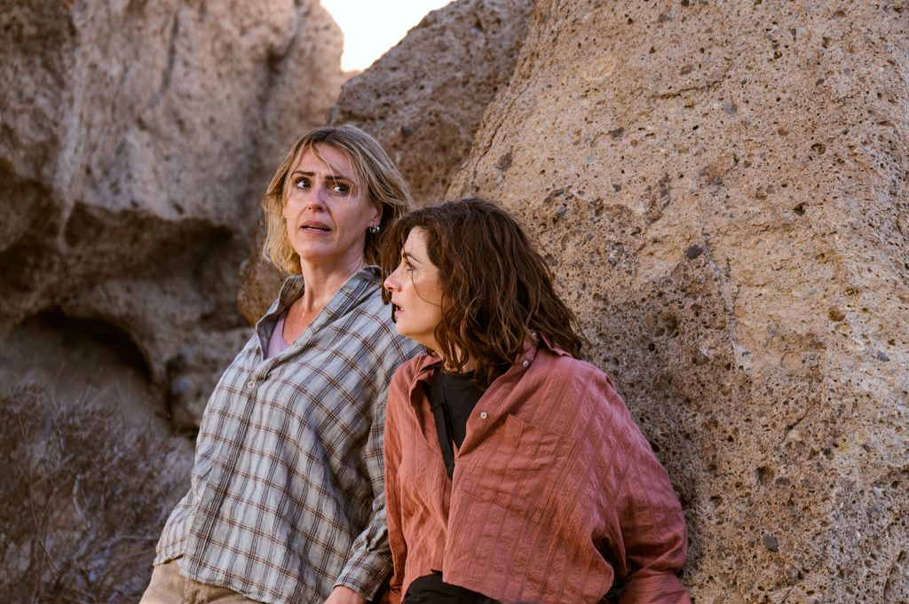 two women hiding behind rock