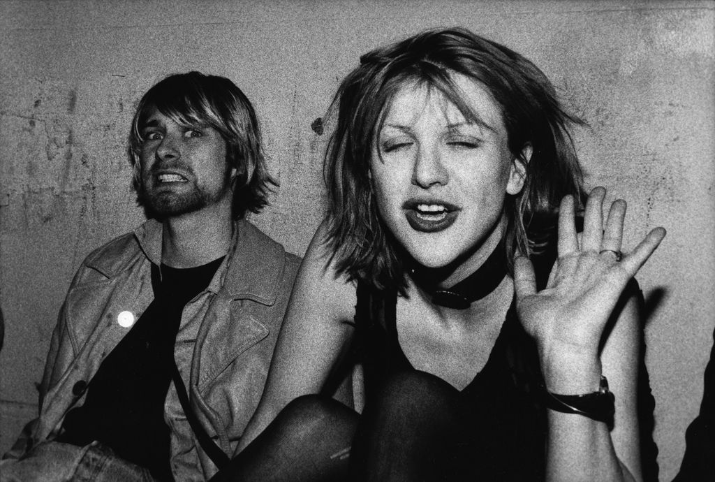 Kurt Cobain et Courtney Love posent pour la photographie, Kurt grimaçant devant la caméra et Courtney saluant, sur le balcon VIP lors du concert de Mudhoney au Hollywood Palladium le 4 décembre 1992 à Los Angeles, Californie.
