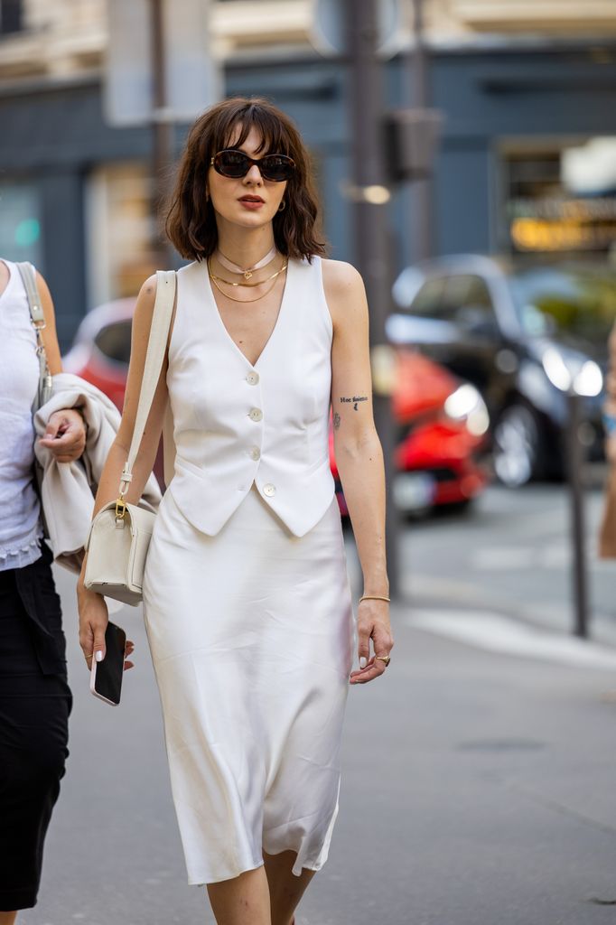 A guest wears white vest, silk skirt, red heels outside RDNT Andre Tan during the Womenswear Spring/Summer 2024 as part of  Paris Fashion Wee