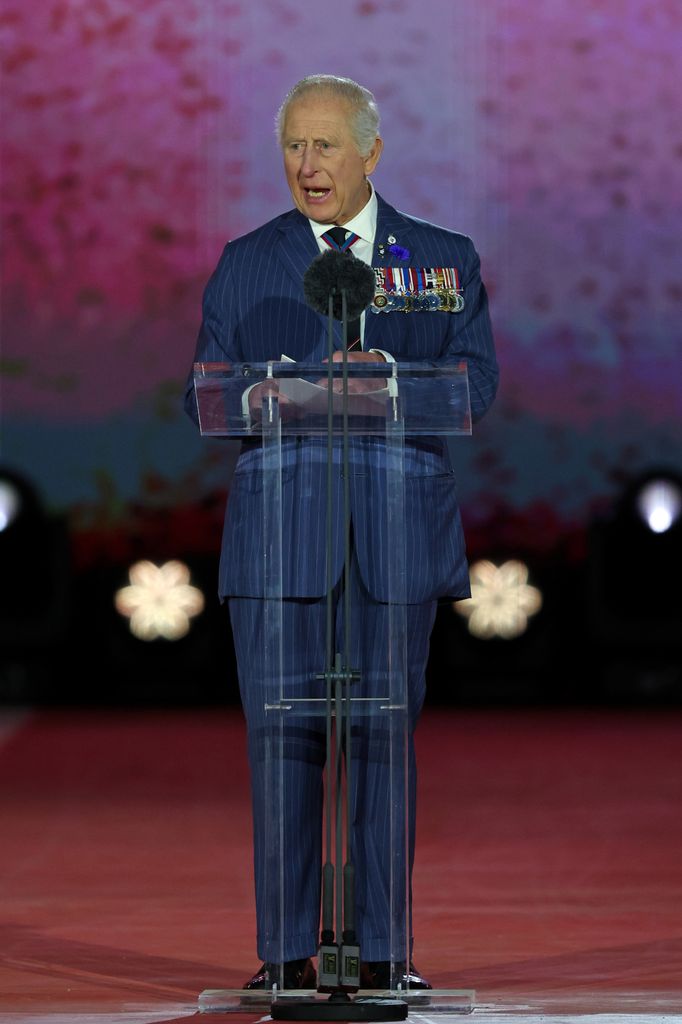 King Charles giving a speech in a blue suit with military medals