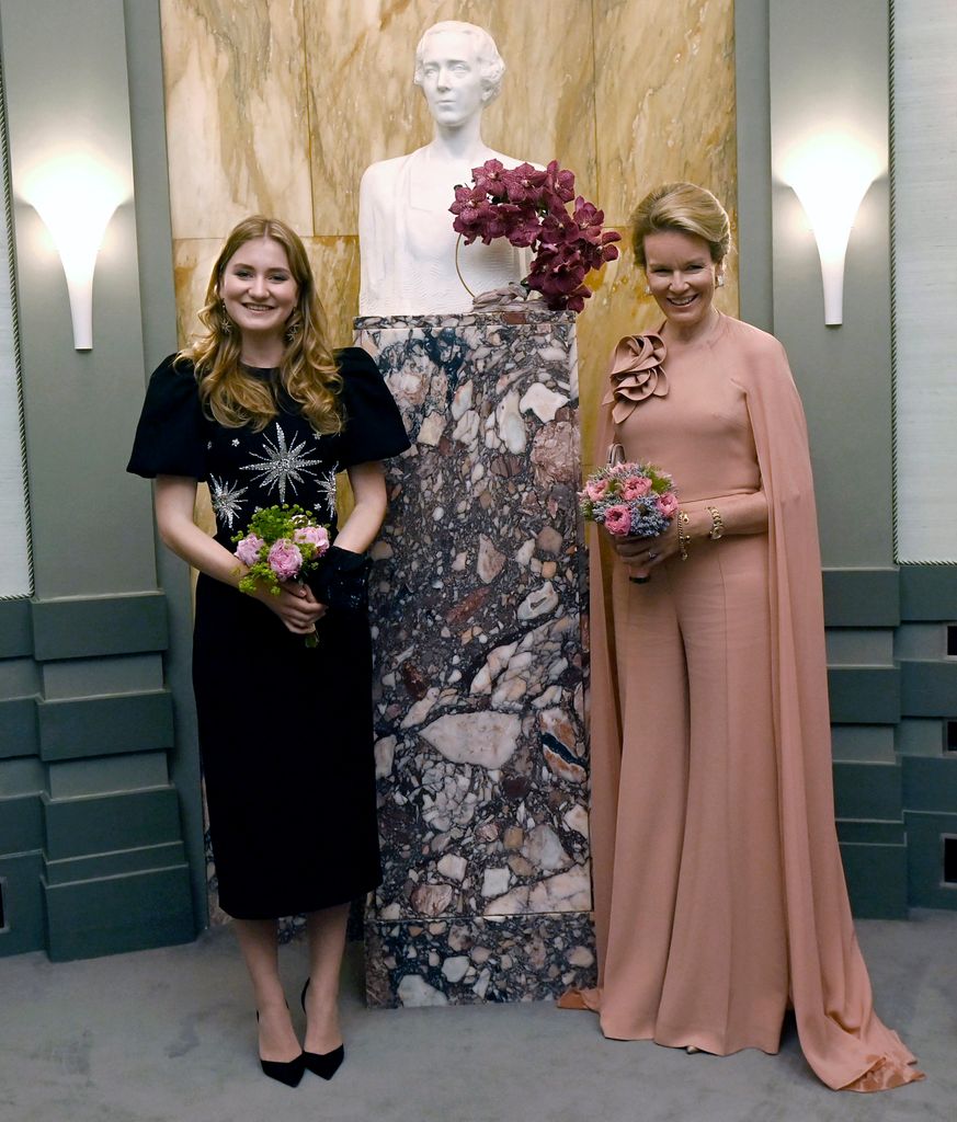 Princess Elisabeth and Queen Mathilde wearing evening dresses and holding flowers