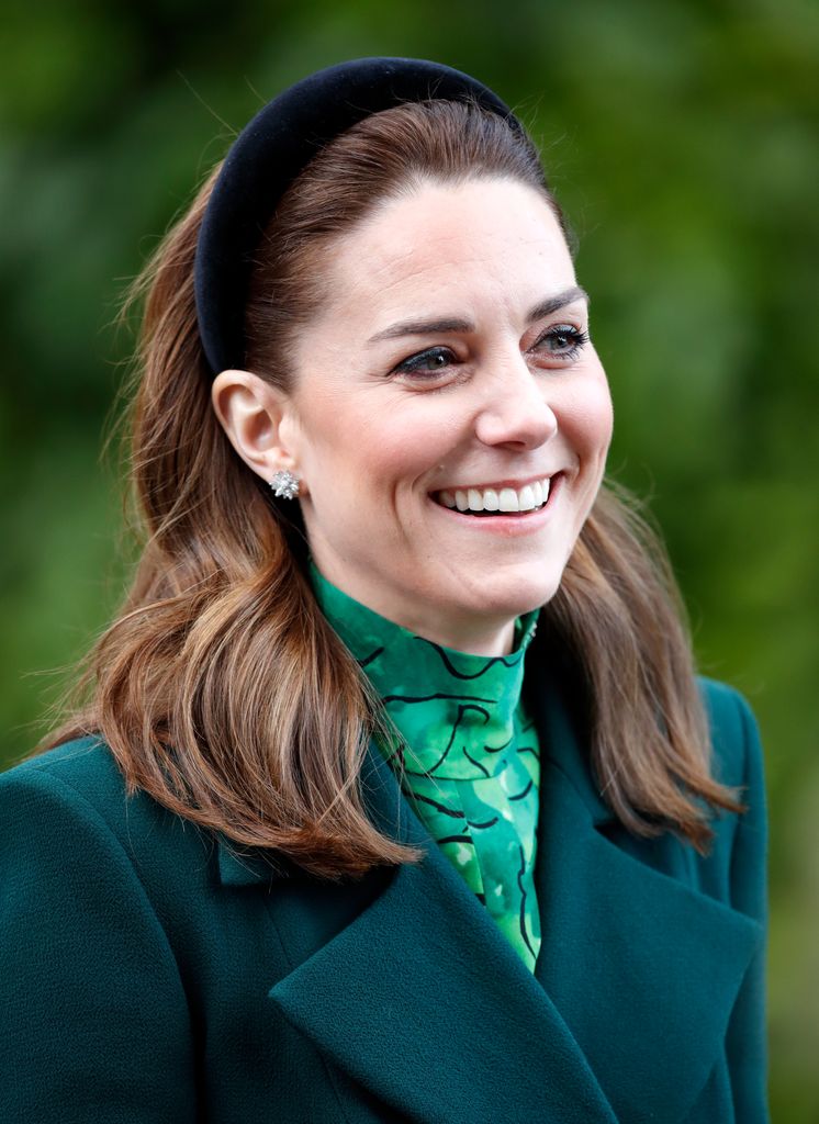 Catherine smiling shoulders up in green coat and black headband