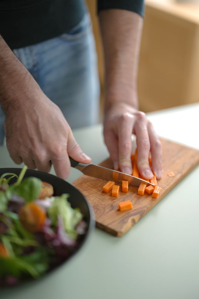 Man cutting a carrot into cubes while preparing a tasty salad 