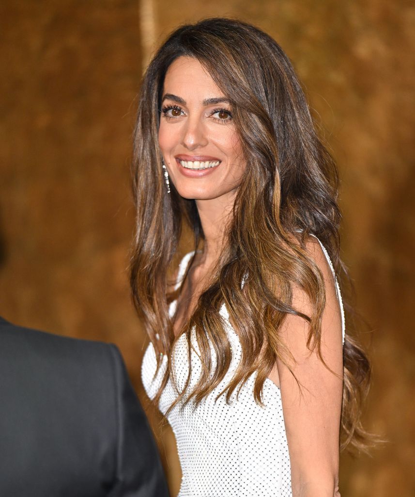 Amal Clooney smiling in a white dress