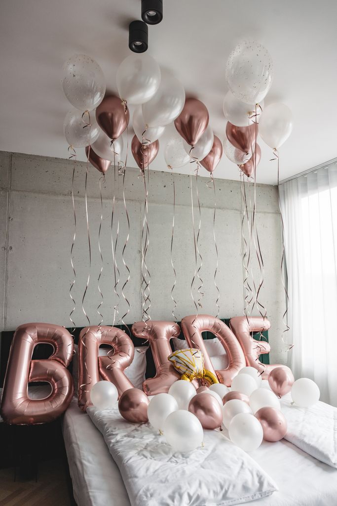 Beautiful balloons on a bed in a hotel room spelling the word bride.