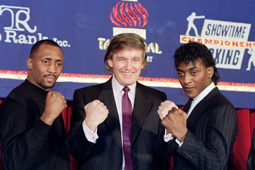 Donald Trump (C) puts his fists in the air as Thomas "The Hitman" Hearns (L) and Michael "The Silk" Olajide (R) announce a super middleweight title fight in 1990