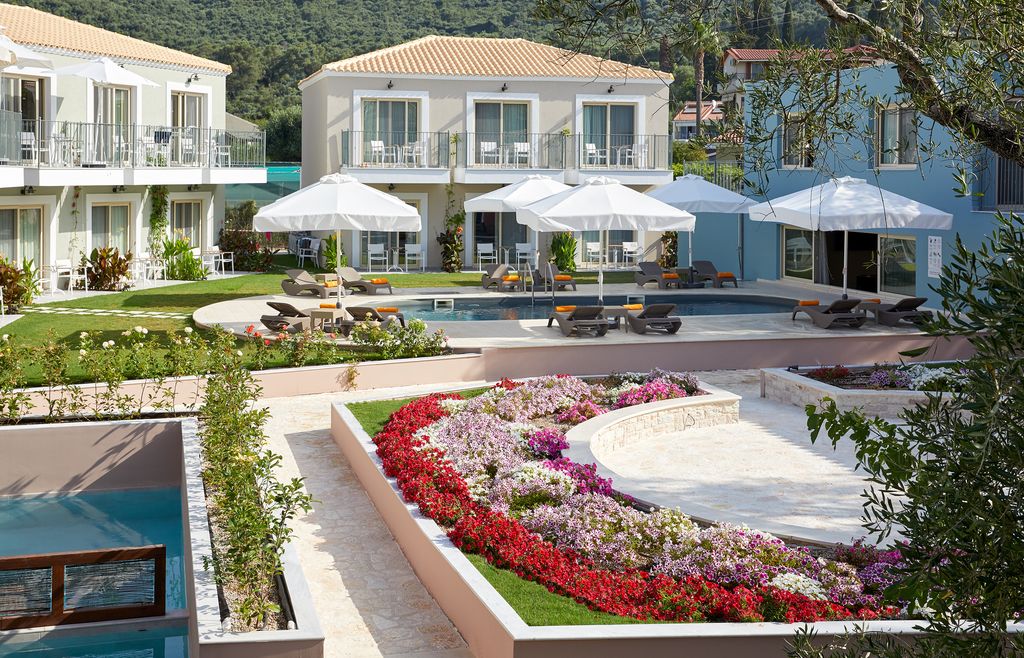 Hotel buildings around a pool and colourful flower beds