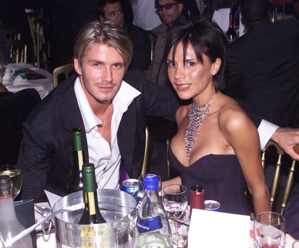 Victoria Beckham with short hair smiles alongside her husband David Beckham 
