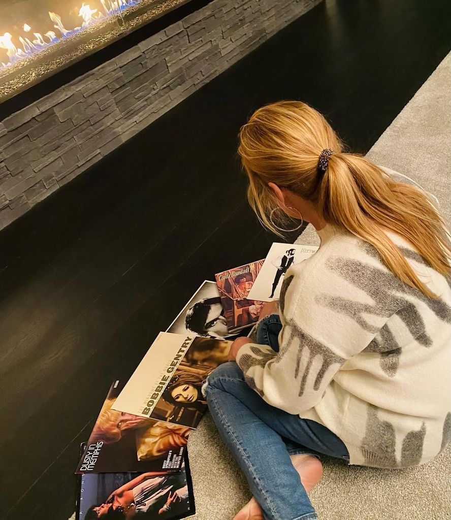 Trisha Yearwood sits on the floor in front of the gas fireplace