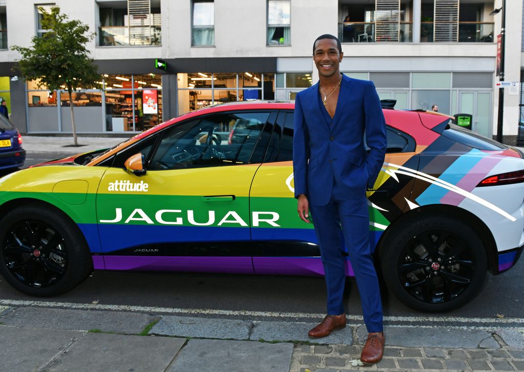 Michael Gunning stood in front of a Jaguar-branded car decorated with the Progress Pride flag