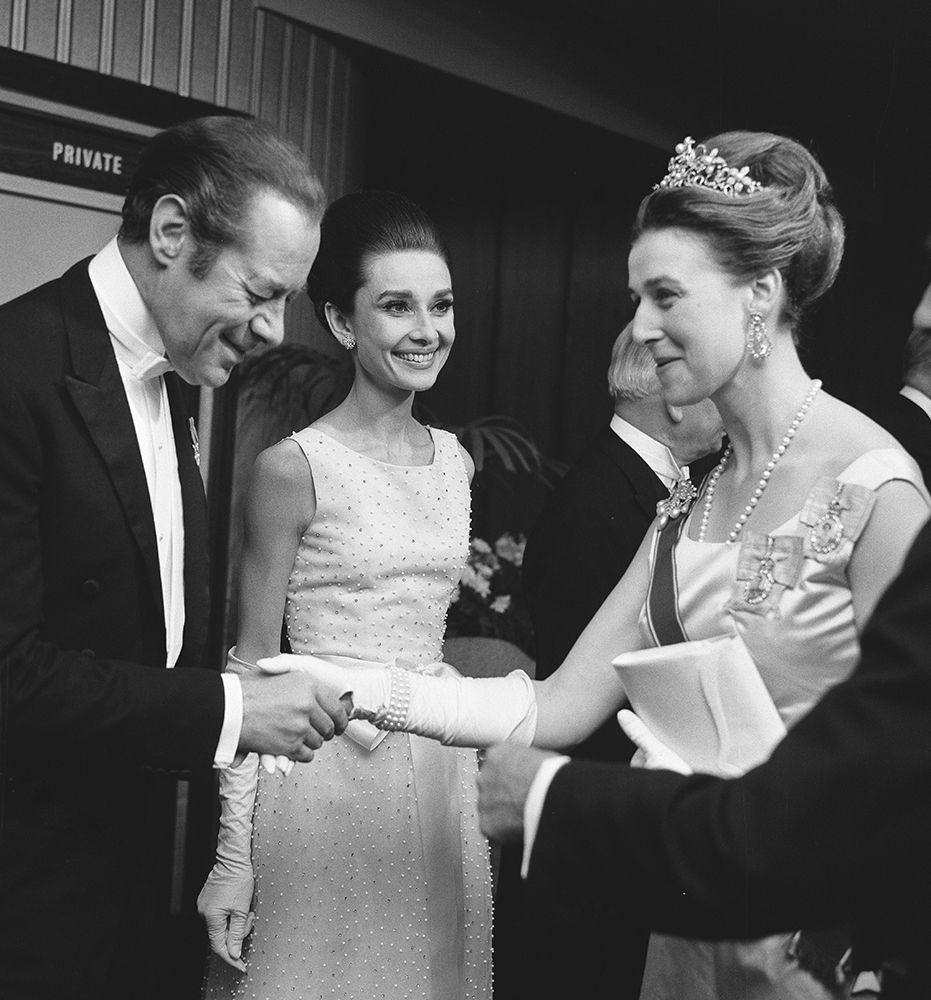 Princess Alexandra shaking hands with Rex Harrison as Audrey Hepburn watches