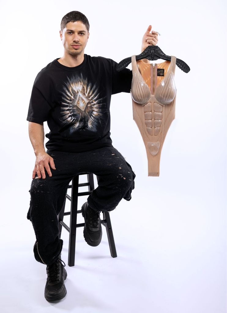 Asher Levine poses with the bodysuit he created for Doja Cat for her Coachella performance