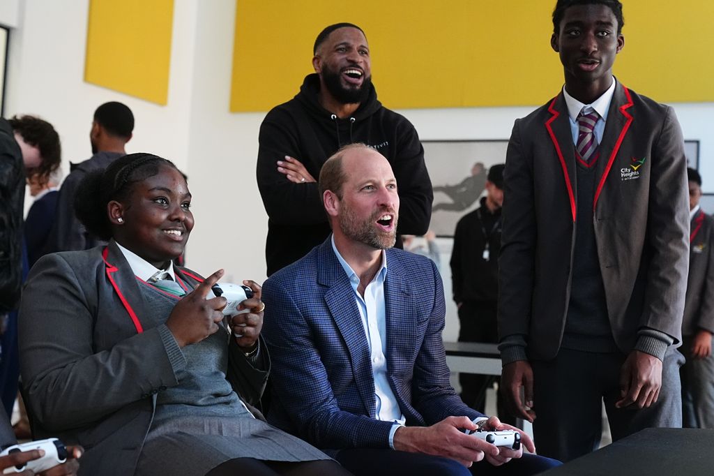 Prince William looking engaged playing a video game with two other students at Mentivity Community centre