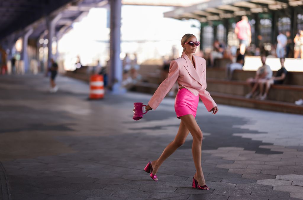 Leonie Hanne is tonal outfit goals in her neon pink mini skirt, baby pink blazer, pink Balenciaga Hourglass bag and matching metallic heels at New York Fashion Week